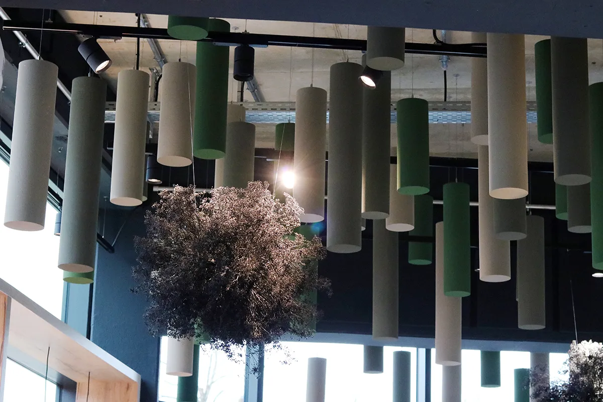 Akustikzylinder von der Decke hängend, gefärbt in Grau und Grün