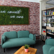 Moosbild mit Leuchtschrift vor Backsteinwand im Loungebereich