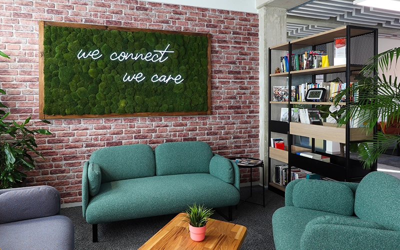 Moosbild mit Leuchtschrift vor Backsteinwand im Loungebereich